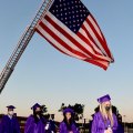 Lemoore High grads march in to Tiger Stadium past the flag.